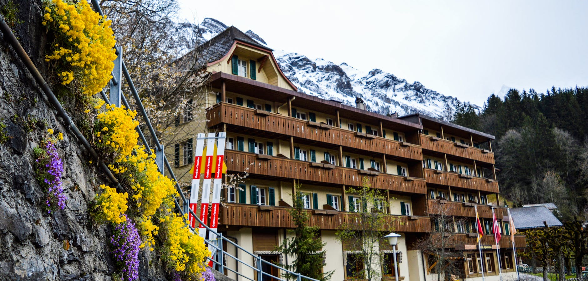 Ein Schweizer Hotelgebäude mit einem stilvollen Eingangsbereich, vor dem Hoteliers und Gäste im Gespräch stehen, symbolisiert den Konflikt zwischen traditionellem Hotelbetrieb und Online-Buchungsplattformen.