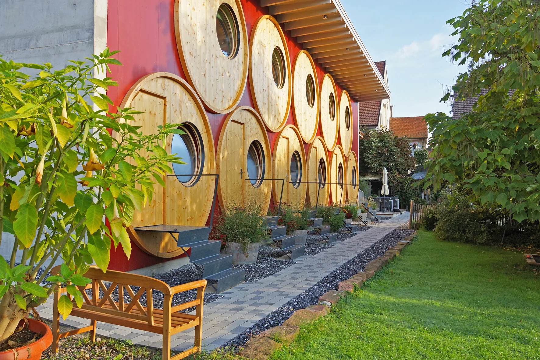Exterior of the WeinFassHotel showing distinctive wine barrel-shaped wooden facades in warm afternoon light.