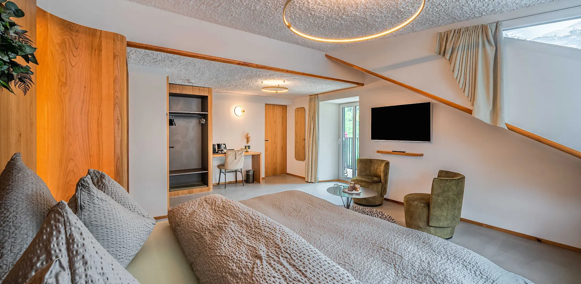 Elegantly designed hotel suite bedroom with floating wood-framed bed, warm timber wall panels, and green moss art piece reflecting the natural alpine environment.