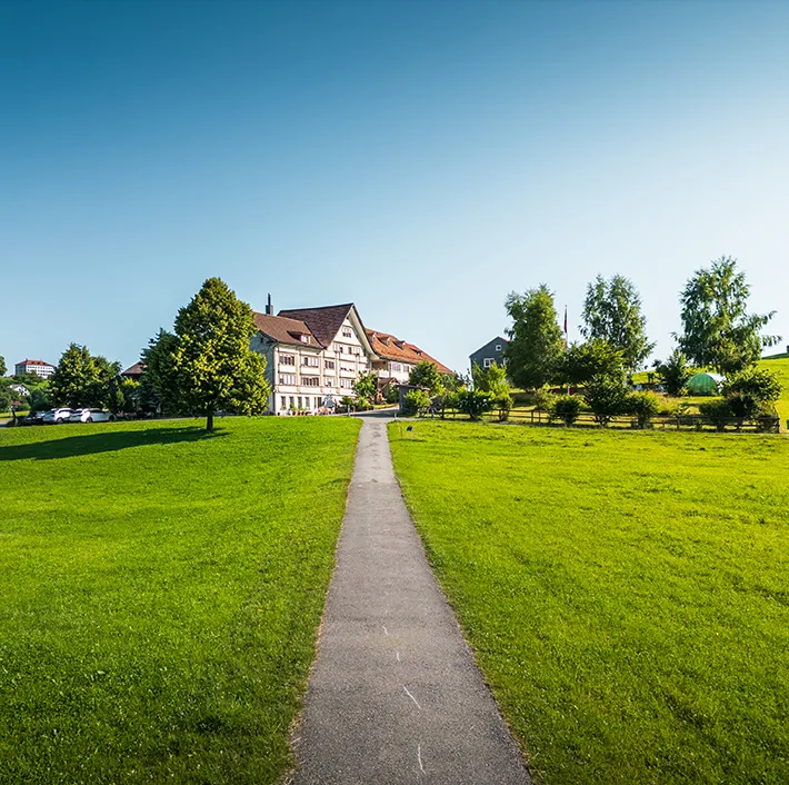 Hotel entrance signage nestled in lush Appenzell countryside, welcoming guests with authentic regional charm.