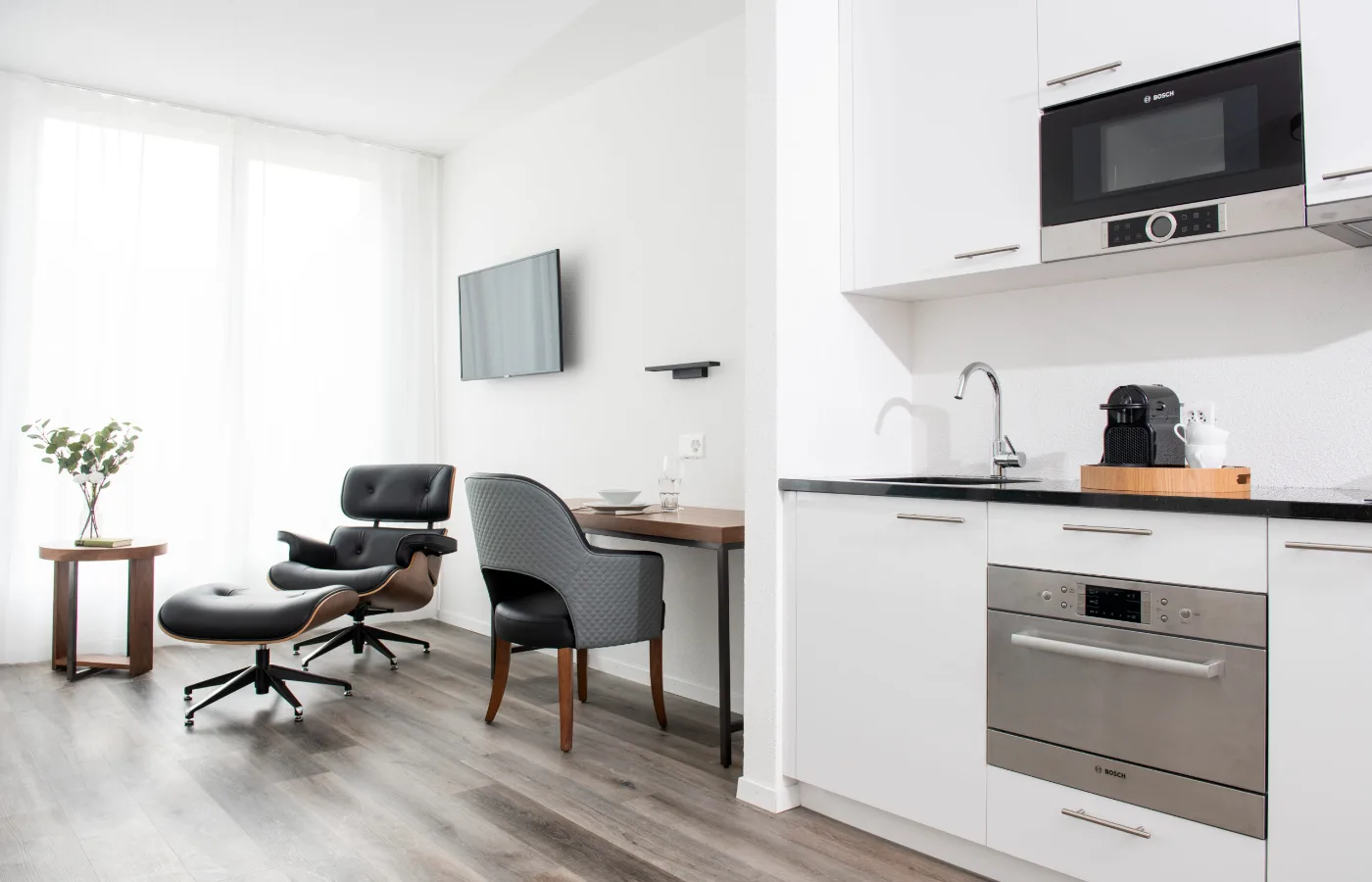 Studio interior blending bedroom, kitchen, and lounge with designer furniture, representing premium business apartment experience.