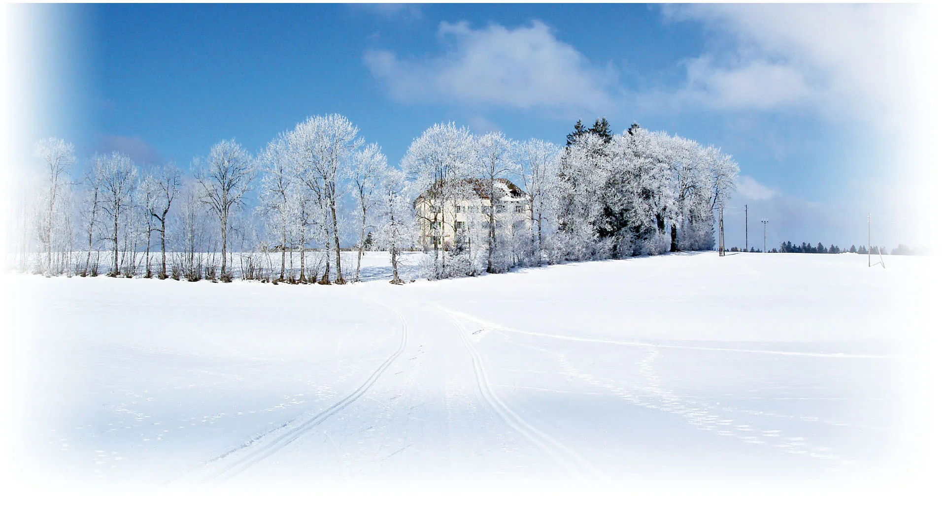 The manor stands amid frost-covered trees in a pristine winter landscape with cross-country ski tracks.