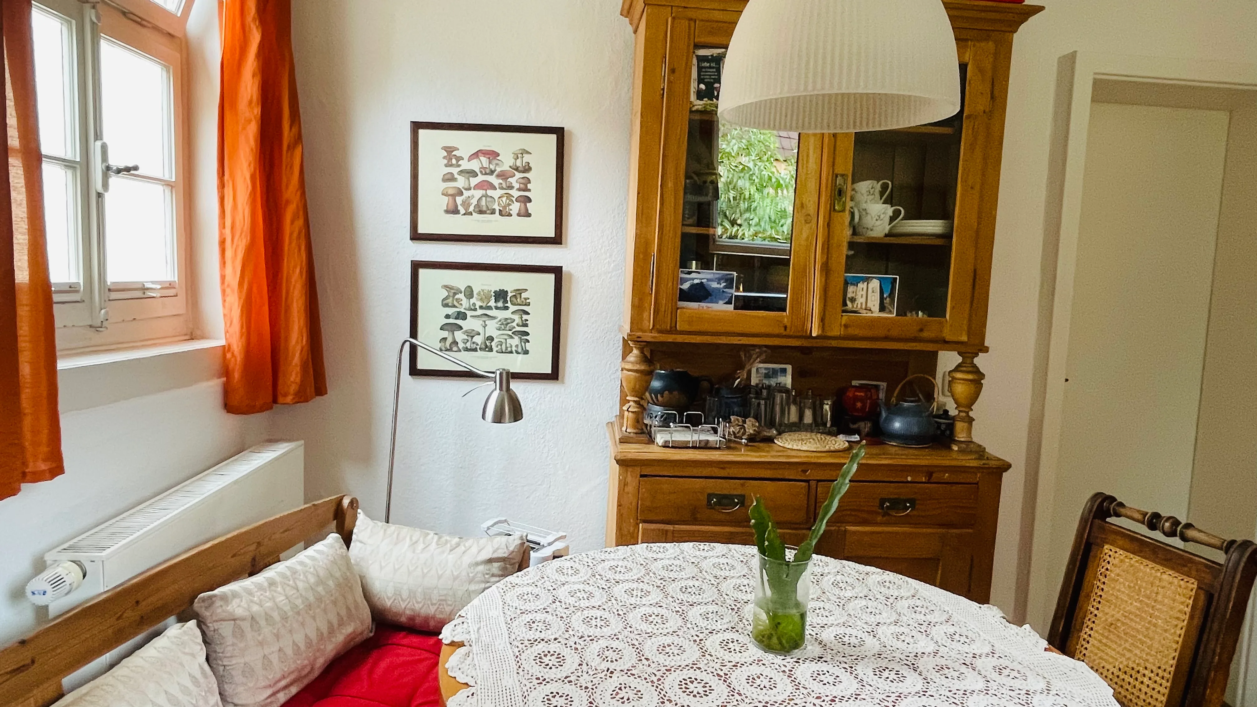 The guesthouse owner stands warmly at the historic wooden entrance door of the property.
