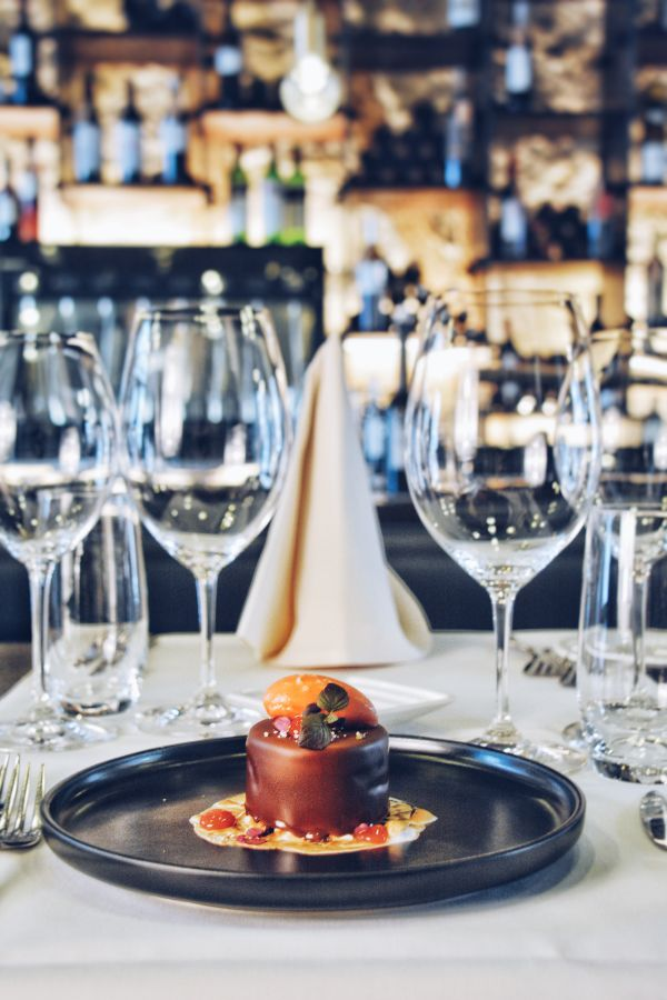 Ein elegantes Gourmet-Restaurant mit fein gedeckten Tischen, gedämpfter Beleuchtung und einem gastronomischen Ambiente, das gehobene kulinarische Erlebnisse für Hotelgäste symbolisiert.