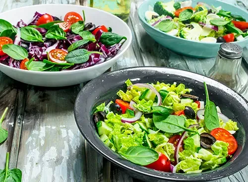 Multiple bowls of hearty soups and chickpea-and-greens dishes presented on a serving counter.