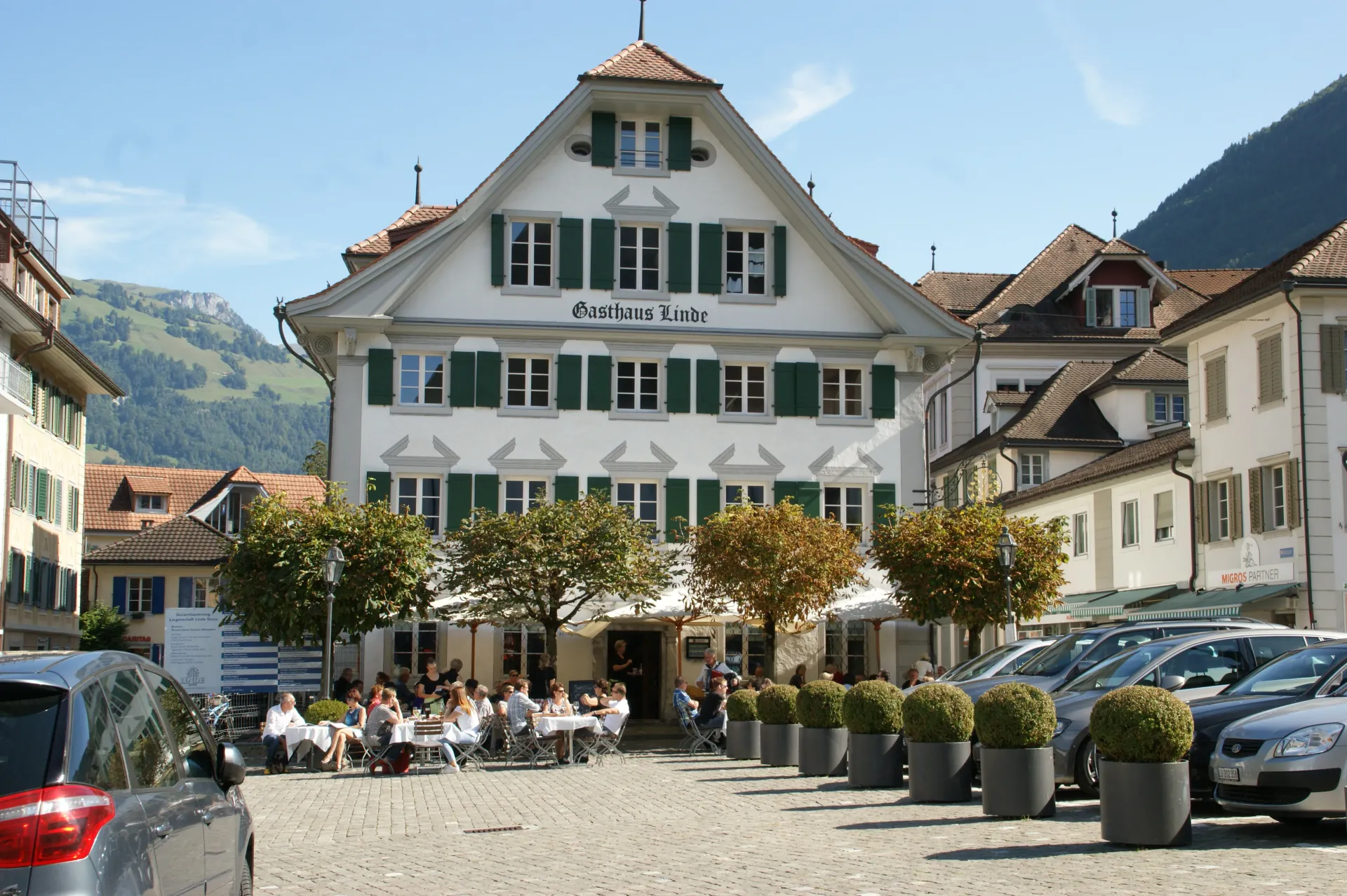 Charming Gasthouse Linde exterior with alpine architecture, terrace seating, and mountainous backdrop epitomizing the restaurant's welcoming charm.