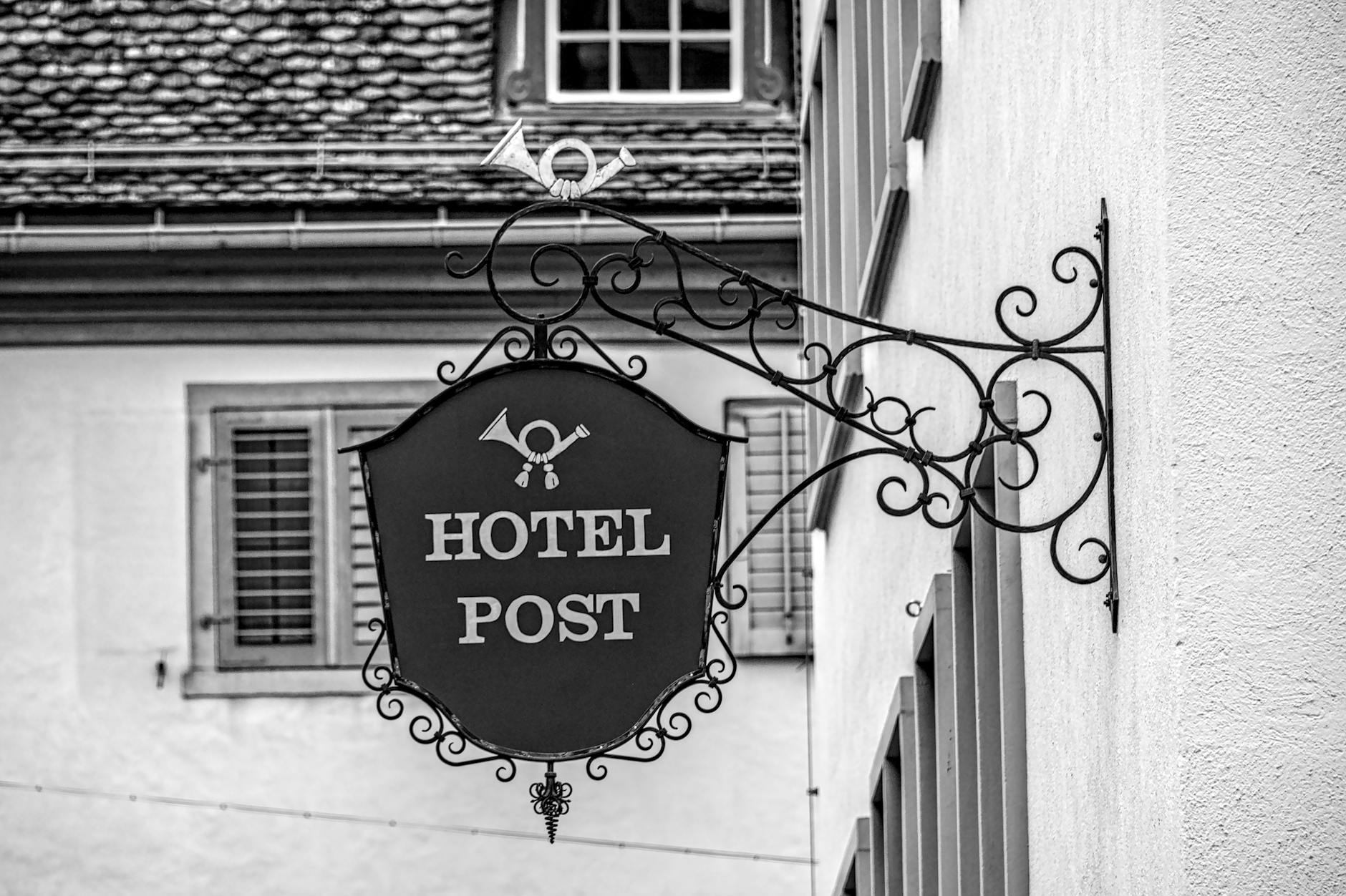 Ein Schweizer Hotelgebäude mit einem stilvollen Eingangsbereich, vor dem Hoteliers und Gäste im Gespräch stehen, symbolisiert den Konflikt zwischen traditionellem Hotelbetrieb und Online-Buchungsplattformen.