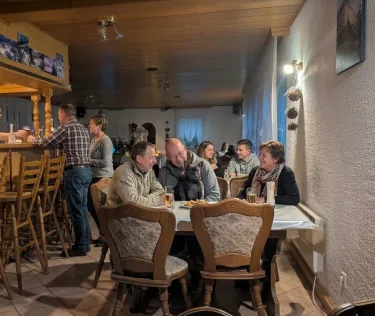 Guests enjoying a warm evening meal together at a cozy rustic restaurant table.