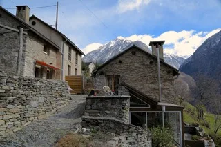 Stone-paved alley between traditional stone houses in the alpine village of Verdabbio.
