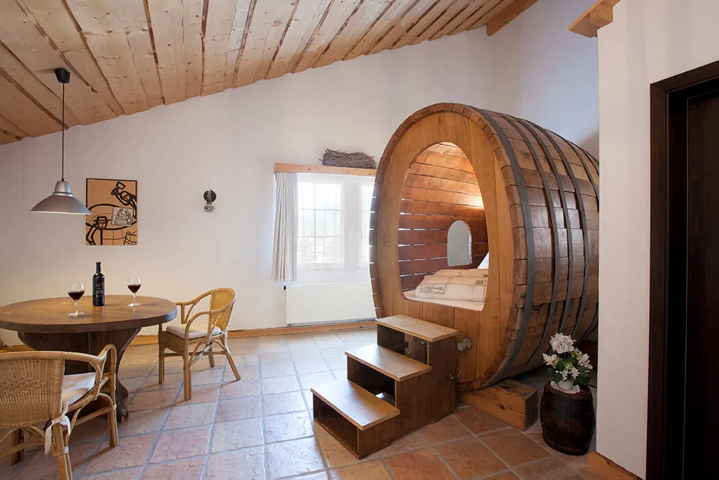 Spacious suite with wooden four-poster bed, antique furnishings, and sloped ceiling.