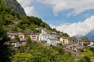 Panoramic view of Verdabbio village nestled on a mountain slope with colorful houses and a church.