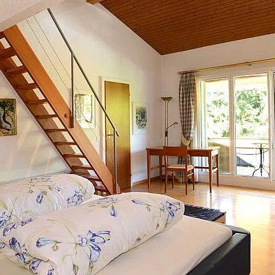 Contemporary bedroom with glass doors opening to nature, combining modern comfort with views of the surrounding Zürcher Oberland landscape.