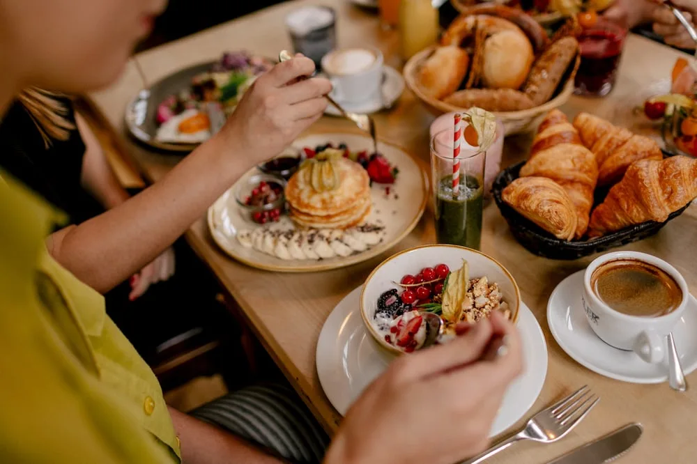 A beautifully presented breakfast spread with pancakes, croissants, berries, yogurt, and fresh coffee.