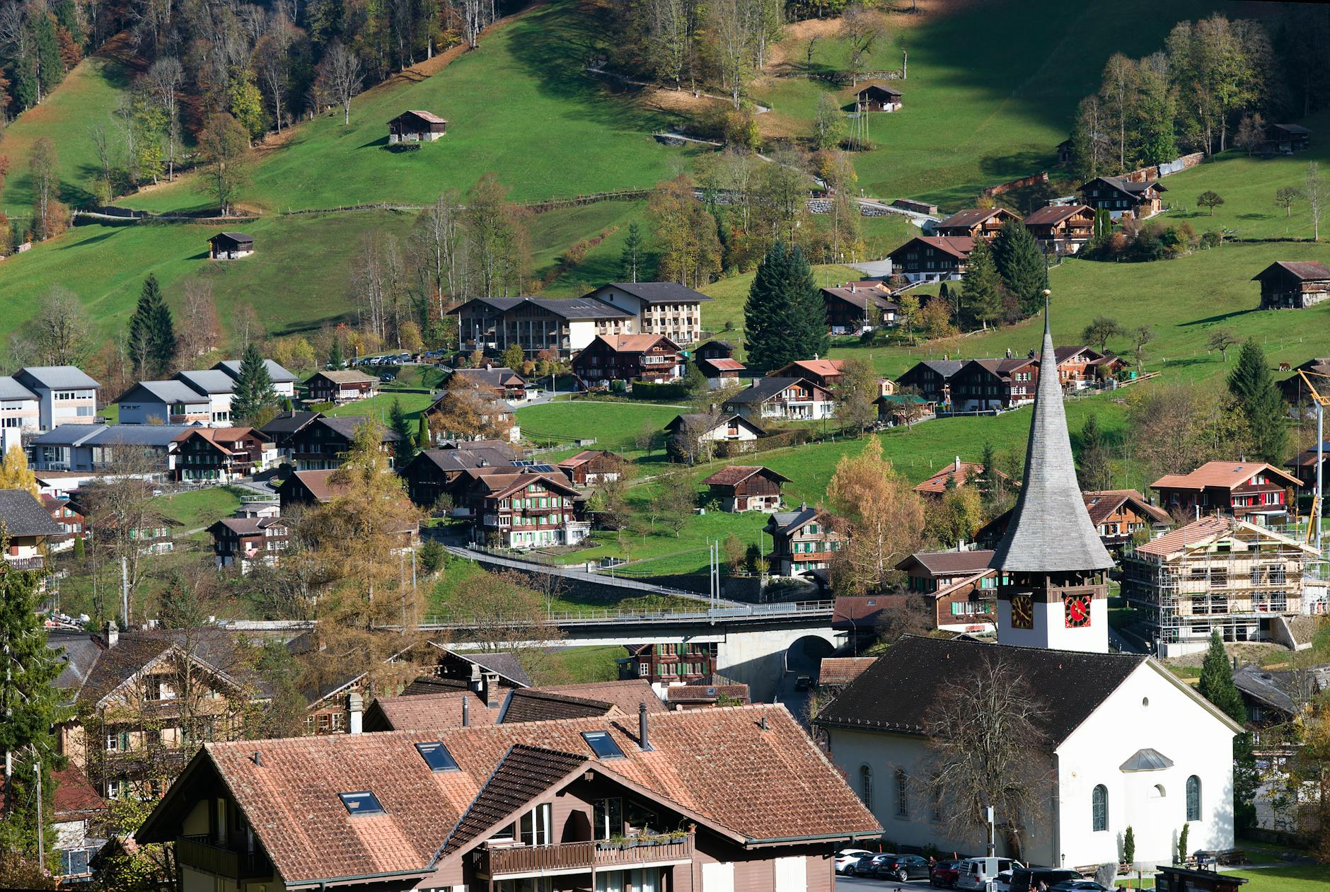Ein moderner, schlanker Turm vor der Kulisse der Schweizer Alpen, umgeben von traditionellen Holzhäusern, der die Spannung zwischen Innovation und Erhaltung im Tourismus symbolisiert.
