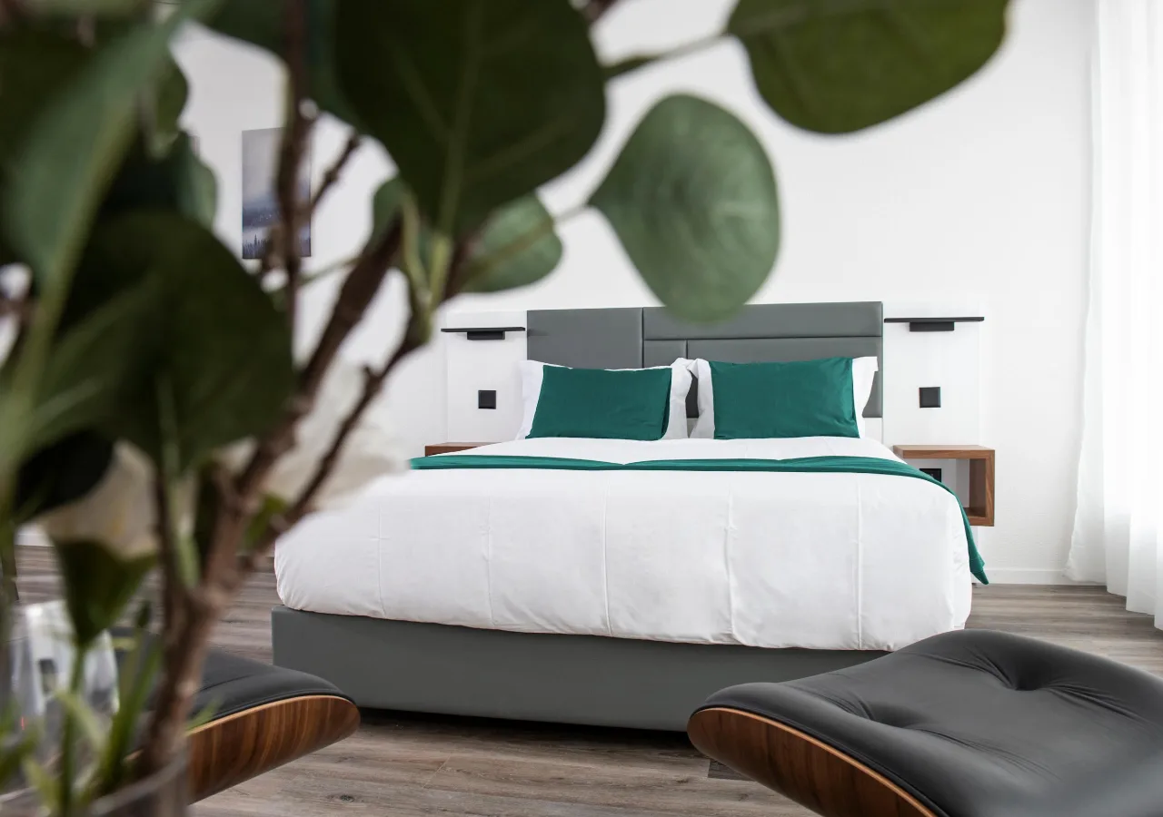 Modern bedroom with teal accents and workspace, embodying home comfort merged with business functionality.
