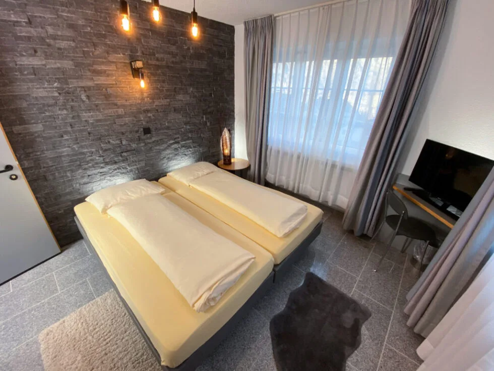 Close-up overhead angle of the double room showing yellow bed, flanking nightstands, and wardrobe.