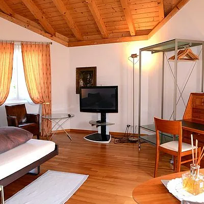 Bright loft-style room with natural light, wooden details, and work desk blending hospitality comfort with functional guest space.